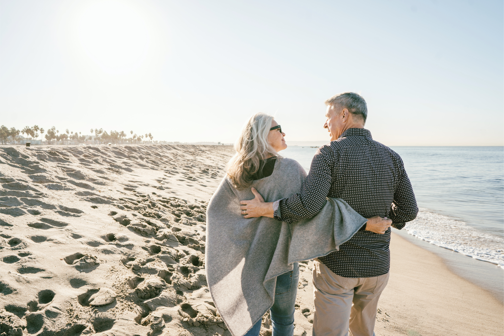 A couple walks on the beach during retirement